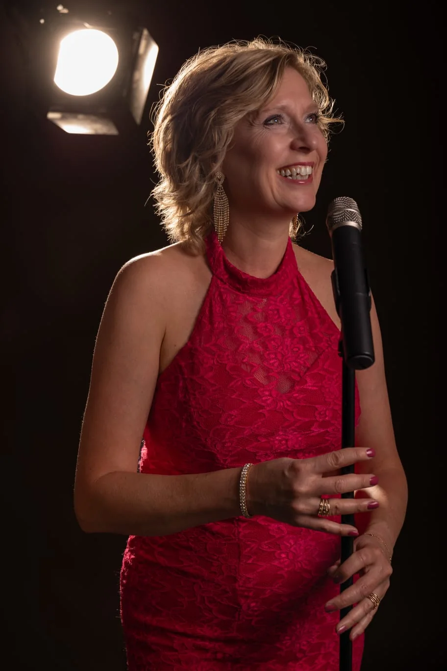 Josefine Wijnhoven zingend in een rode jurk met microfoon