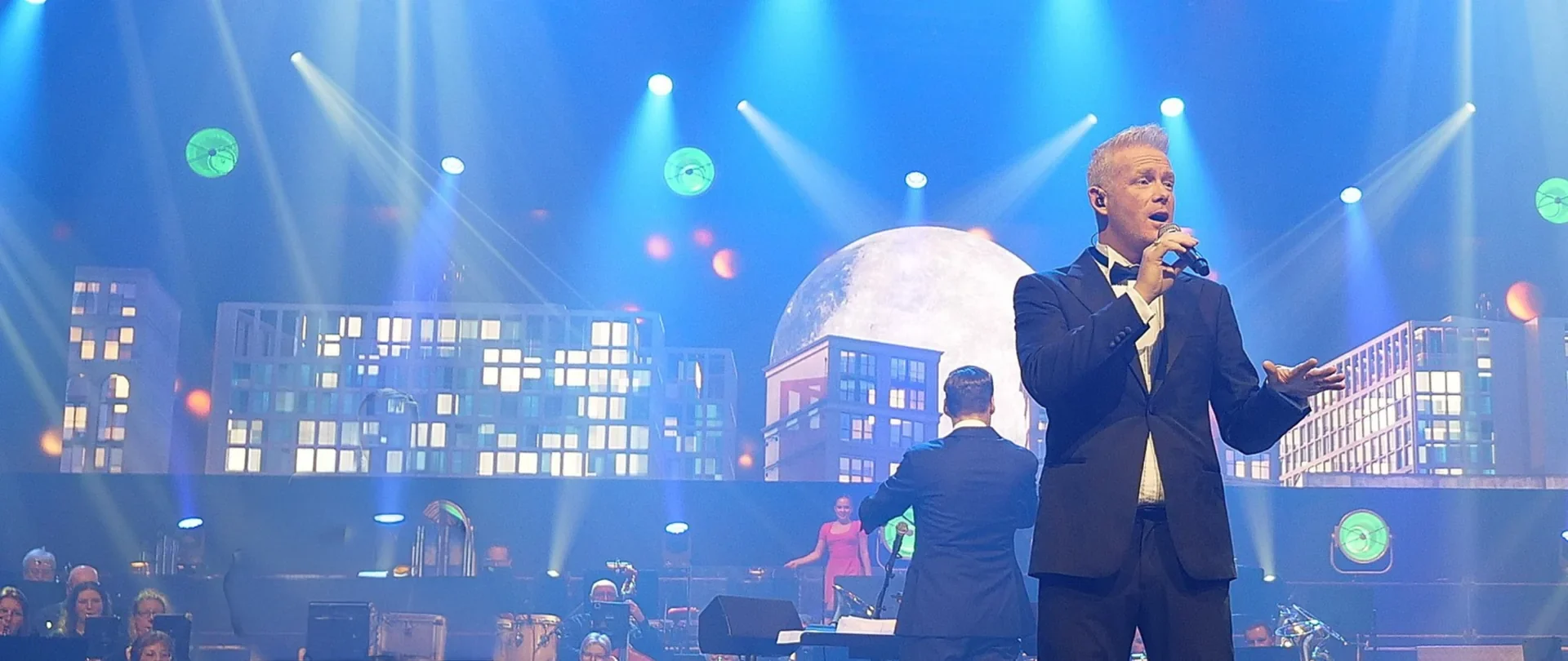 Zanger op een groot podium met blauwe showverlichting en publiek