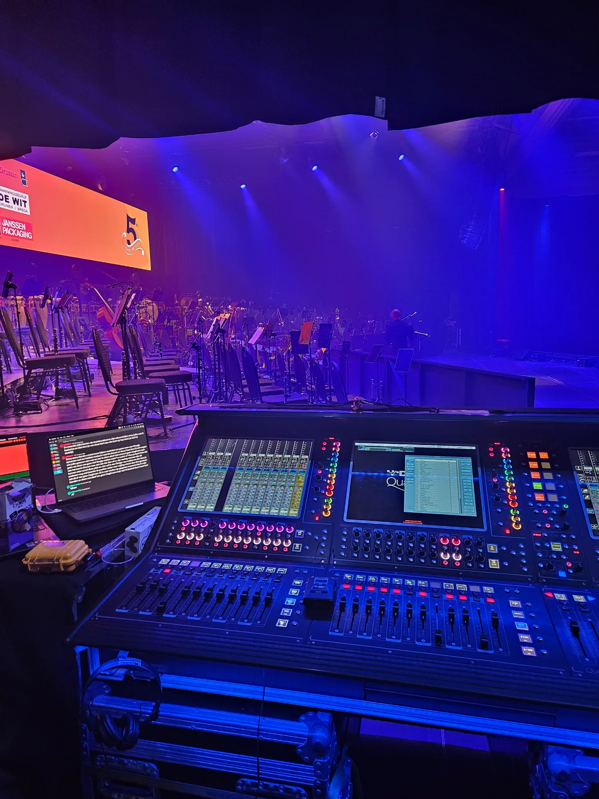 Geluidstafel naast het podium tijdens de opbouw, met de zaal in blauw licht
