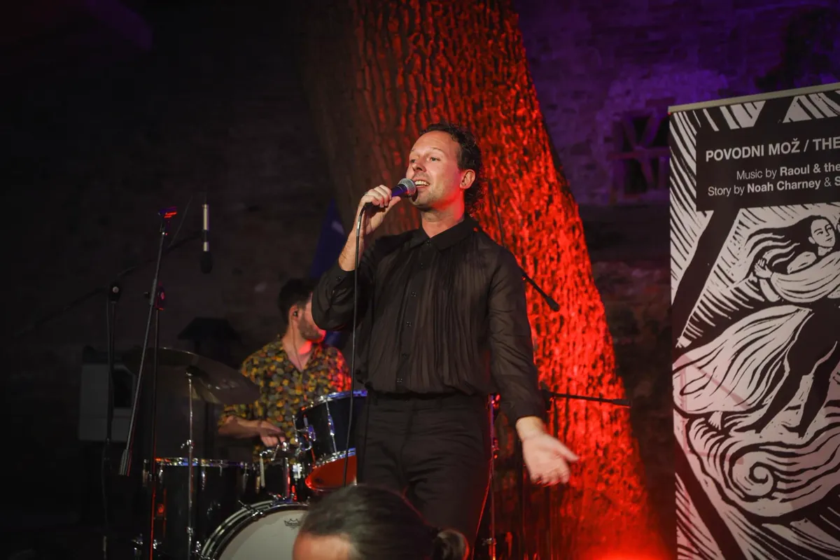 Raoul Wijsma zingend op een podium met band en rode sfeerverlichting